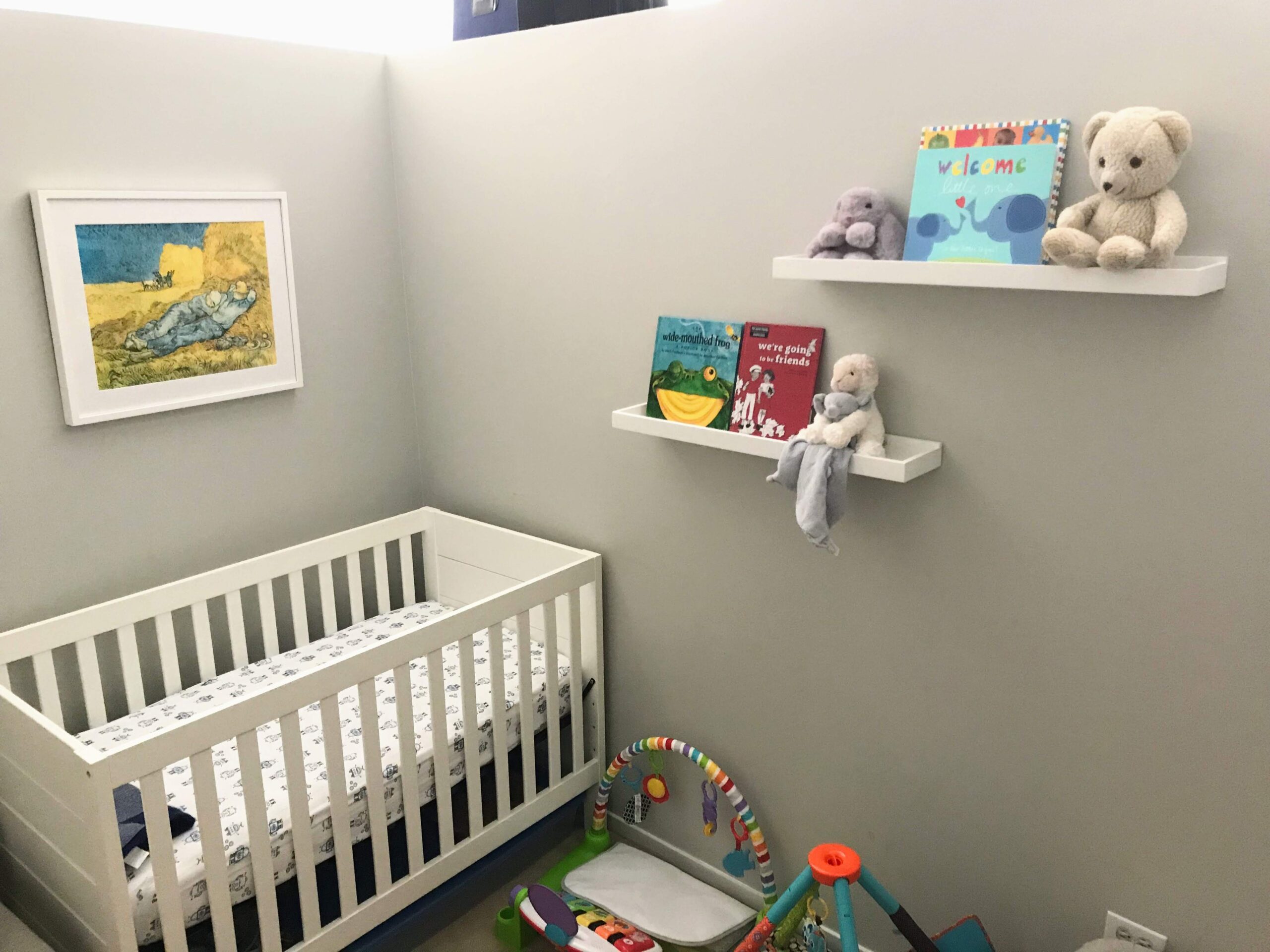 Nursery with custom framed art with books, stuff animals, and a crib